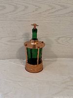 Front and side view of copper music box decanter featuring green glass bottle and copper stopper in place.