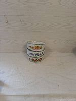 Three nested enamel-coated metal bowls with floral patterns arranged stacked with smallest on top