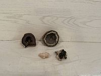 Four rock specimens placed on light wood surface showing two geodes and two mineral specimens