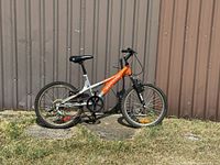 Side view of the orange and silver Impulse Supercycle bike showing frame, tires, and drivetrain.