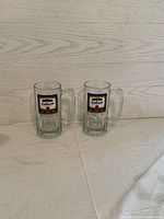 Two clear glass beer stein mugs side by side showing the Labatt logo on the front.