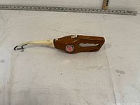 Side angle of the full Popeil Pocket Fisherman compact fishing rod in brown plastic and white rod section with ruler above showing approx length.