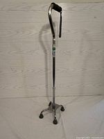Full view of the aluminum quadripod cane with base and handle showing foam grip and wrist strap.