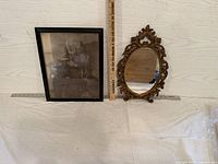 Both framed print and ornate mirror with measuring sticks showing size