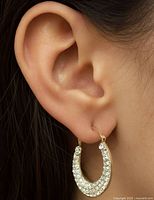 Earring worn on ear to show scale and fit, showing front CZ stone detail and gold metal.