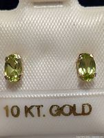 Close-up front view of the pair of oval peridot stud earrings in 10K gold.
