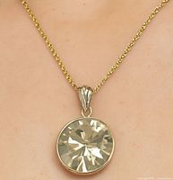 Pendant worn on a gold chain showing size relative to neckline.