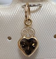 Close-up front view of the 14K gold pendant with heart-shaped smokey quartz gemstone and gold spiral design above.