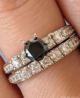 Rings worn on finger showing black diamond solitaire and CZ pavé detail