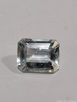 Close up image of single emerald cut aquamarine gemstone showing light blue color and clarity.