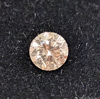 Close-up clear image of a round brilliant cut diamond on a black background showcasing the diamond's facets and brilliance.