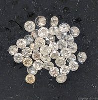 Close-up cluster of loose round diamonds on black pad.