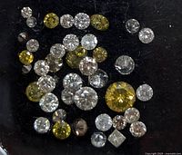 Top-down view of assorted loose diamonds on black background