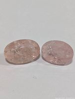 Two oval-shaped light pink to peach Morganite stones placed on a white background.