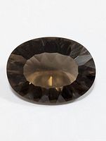 Top-down view of faceted oval shaped smokey quartz gemstone on white background.