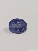 Close-up image of an oval-shaped genuine tanzanite gemstone, showing the natural inclusions and color.