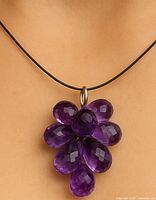 Close-up of necklace worn on a model, showing the amethyst floral pendant and black cord.