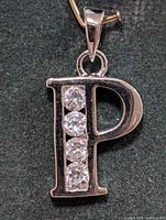 Front close-up showing polished sterling silver 'P' shaped pendant with four clear cubic zirconia stones vertically set.