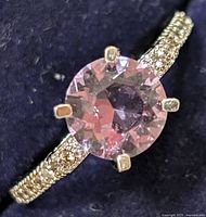 Close-up top view of the silver ring with round amethyst CZ center stone and textured band with small stones.