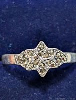 Close-up image of the silver marcasite ring front face on dark blue background showing symmetrical floral pattern with marcasite stones.