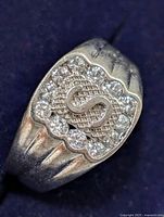 Close-up side angle showing raised 'S' monogram and clear CZ stones on silver ring.