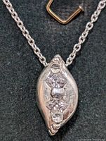 Close-up of sterling silver pendant showing three clear cubic zirconia stones and silver chain.