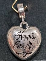Front view of silver heart-shaped locket pendant showing the engraving 'Happily Ever After'.