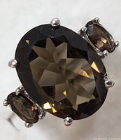 Close-up of the large oval faceted smokey quartz center stone with two smaller side stones set in a polished sterling silver band.