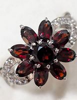 Close-up view of garnet stones set in flower arrangement on sterling silver band with cubic zirconia accents.