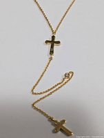 Gold-tone chain necklace with two cross pendants and two small clear CZ accent stones shown laid out flat on white background.
