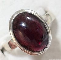 Close-up image of the silver ring showing the oval cabochon garnet stone with deep red color and bezel silver setting.