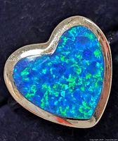 Close-up image of a heart-shaped ring with a bright blue and green opalite stone set in polished sterling silver.