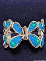 Close-up image of sterling silver ring with blue-green opalite inlaid butterfly design on a silver band.