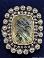 Close-up front view of rectangular faceted lemon quartz set in a beaded sterling silver ring.