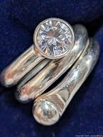 Close-up photo of silver ring showing cubic zirconia stone in bezel setting and smooth spiral band