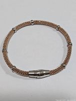 Silver mesh bangle bracelet with cylindrical clasp and round accent beads.