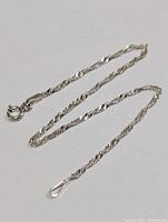 Full view of the silver twisted rope chain bracelet laid flat against a plain background showing clasp and chain detail.