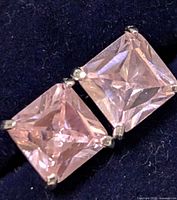 Close-up image of one square pink cubic zirconia set in silver prong setting for the earring.