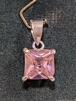 Close-up of square-cut pink cubic zirconia stone set in silver pendant with bail
