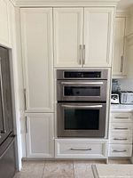 Full view of white panel kitchen cabinets showing tall pantry module on left, built-in double oven, and lower drawer module
