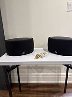 Pair of Klipsch Synergy S1 Surround bookshelf speakers with cables on a table.
