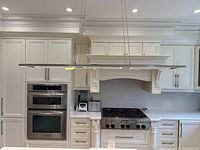 Kitchen installation view showing the rectangular LED light fixture hanging above counters and stove area with white cabinetry.