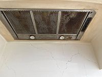 Full view of stainless steel kitchen exhaust fan with three metal mesh filters and control panel on the side.