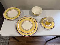 Front view of one place setting: dinner plate, salad plate, bowl, mug and saucer
