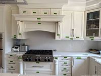 White kitchen cabinets and quartz countertop installed around stove, showing cabinetry modules and countertop surface with subtle gray veining.