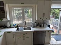 Overall view of upper and lower cabinets installed beneath window with quartz countertop and sink cutout