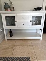 Front view of white sideboard cabinet showing quartz top, two drawers and glass-panel doors