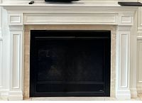 Assembled fireplace mantle surrounding a black fireplace insert inside a room.
