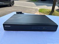 Front view of Hikvision DS-7204HGHI-SH DVR showing black case with Hikvision logo and front USB port.