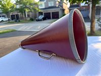 Full side view of the maroon conical megaphone with metal trim and handle showing overall condition